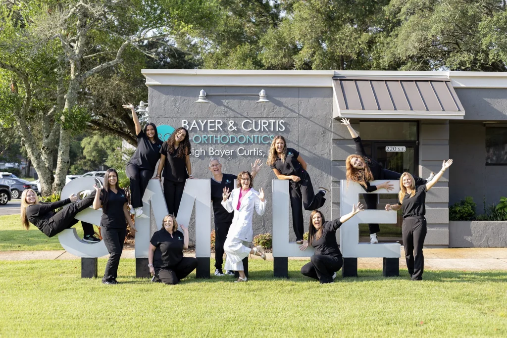 bayer and curtis team posing on Smile statue